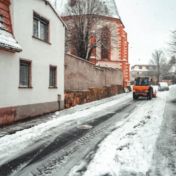 Ein Schneeräumwagen auf einer verschneiten Straße.