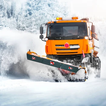 Ein Schneeräumwagen auf einer verschneiten Straße.